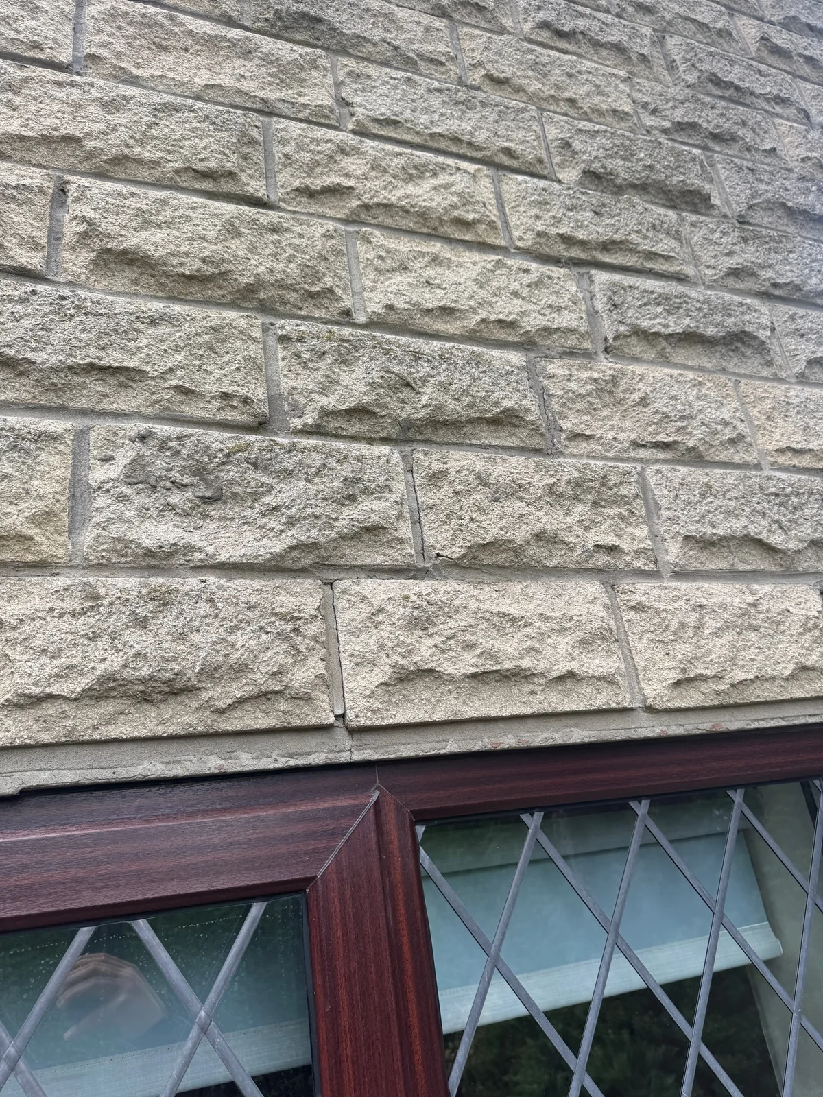 Cracking through masonry and the lintel above a window.