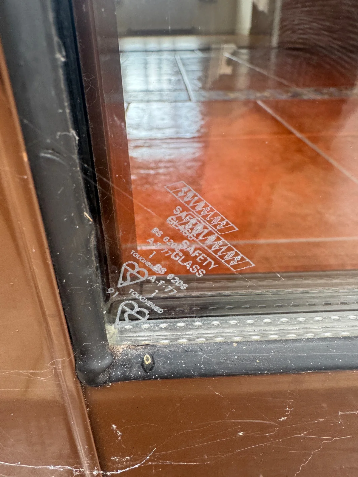 A marking identifying toughened safety glass is visible near the corner of a glazed frame.